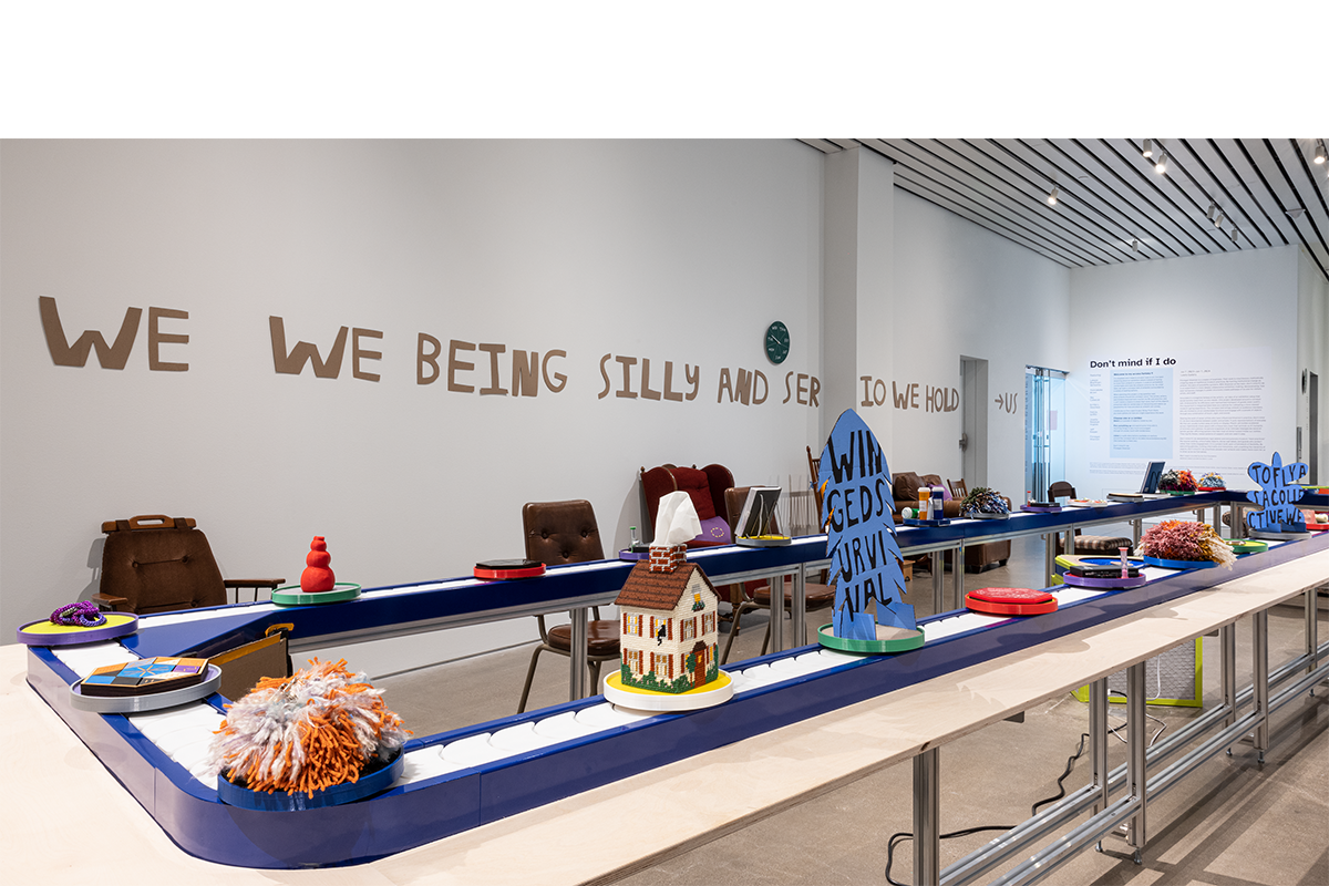 Photo of the exhibition featuring art from the show moving on a conveyor belt.