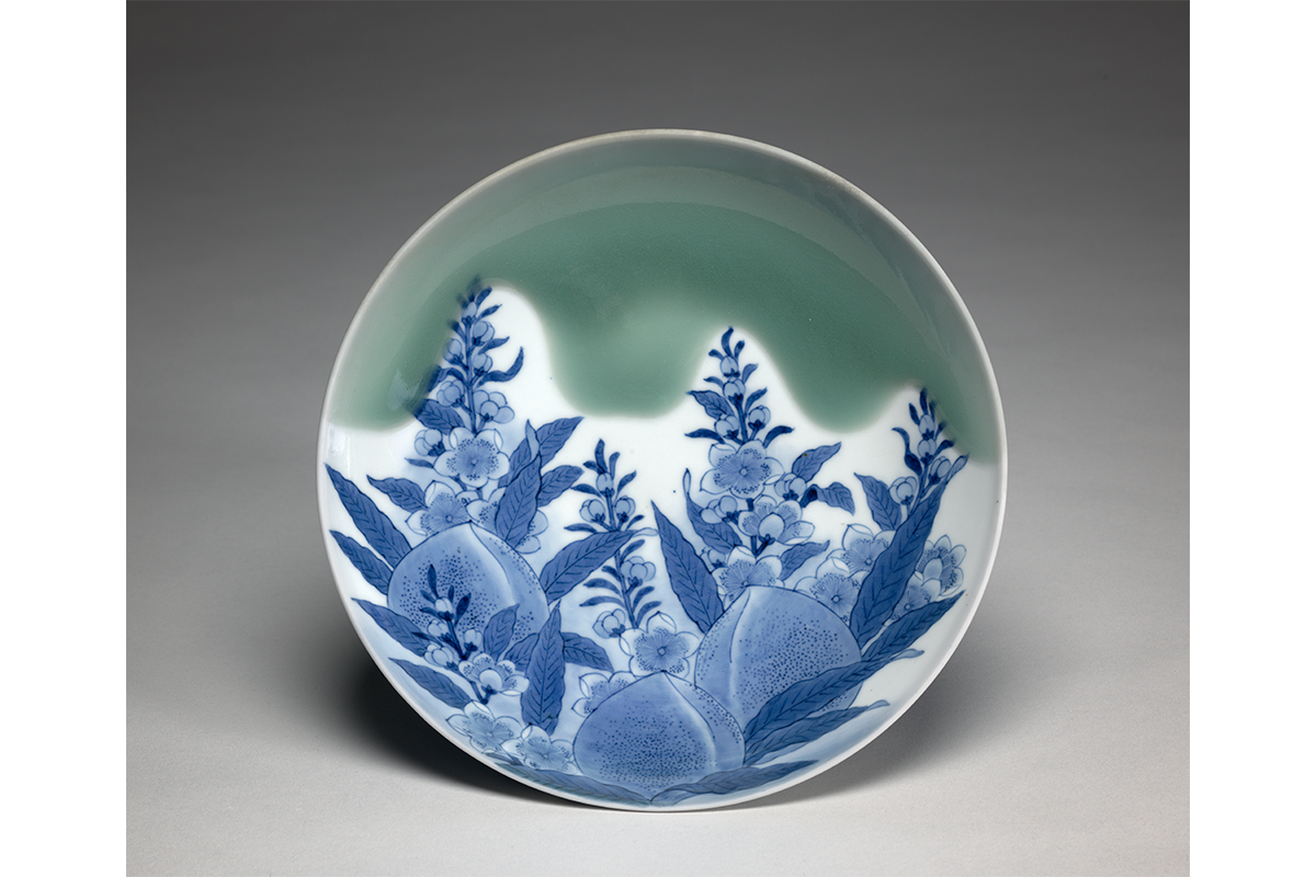 Dish with a drawn glaze of blue peaches, and a green glaze on the top of the dish.