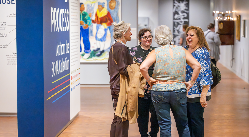 Four older women chatting in the Worlds in Process gallery