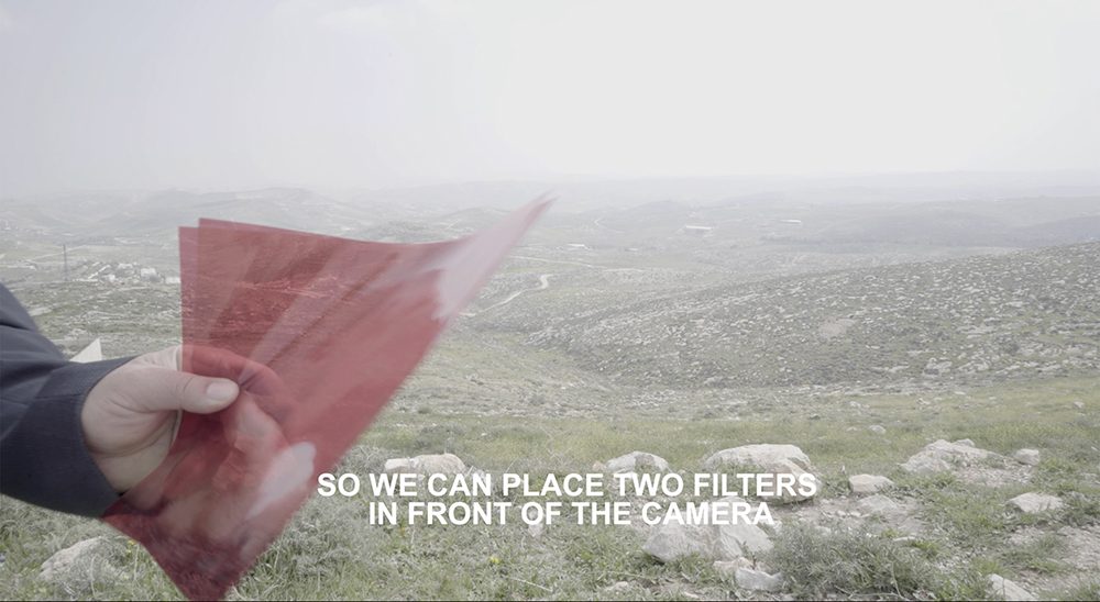 Photo of a foggy landscape with a hand on the left side up close holding sheets of red film
