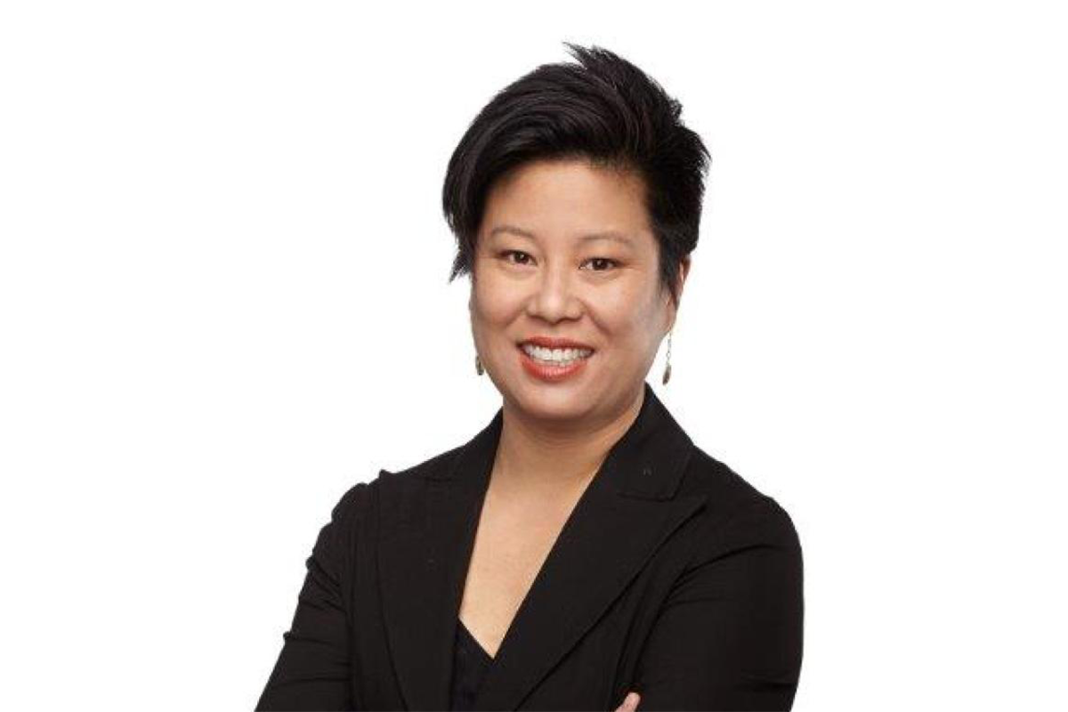 Portrait of a smiling person with short black hair and a black suit coat