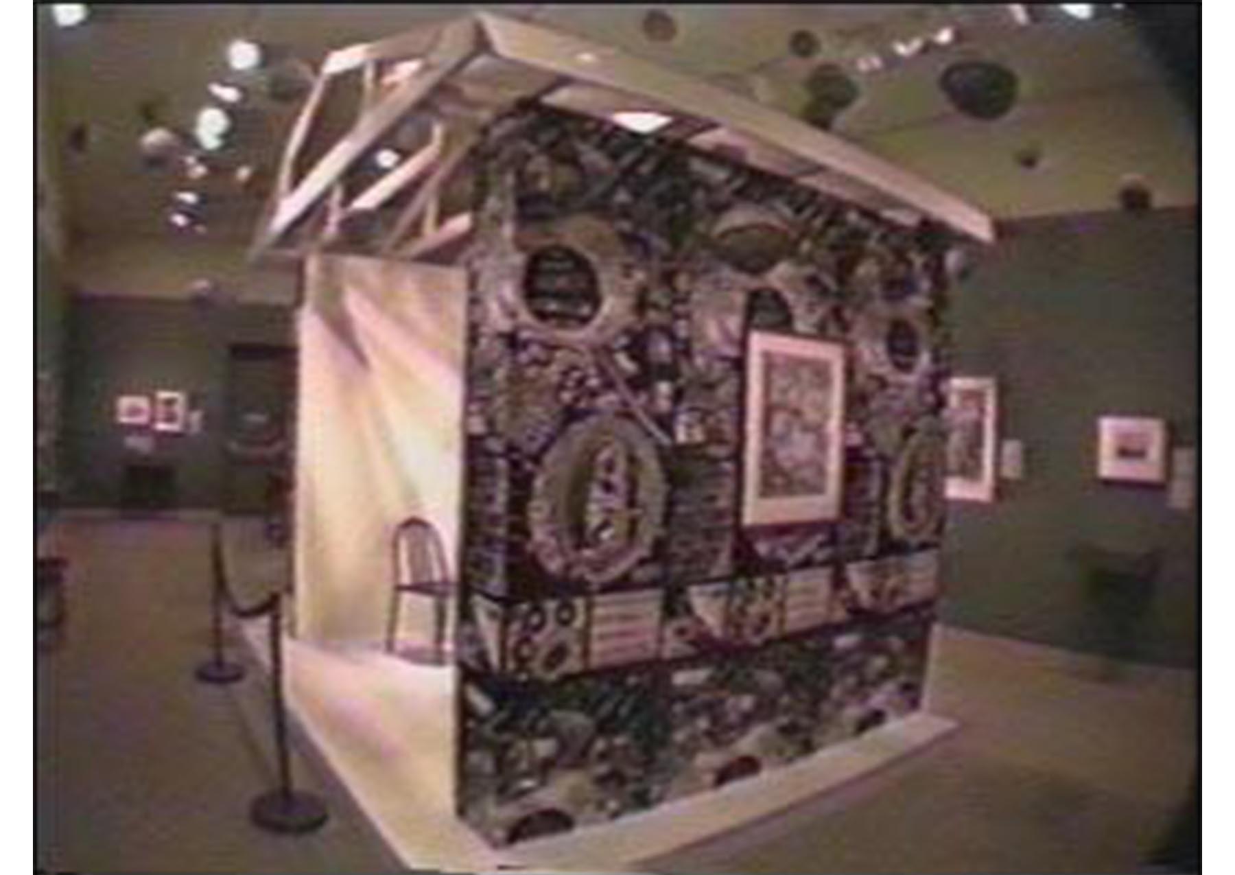 installation in an art gallery. house-shaped structure with black and white large print draping along its edges