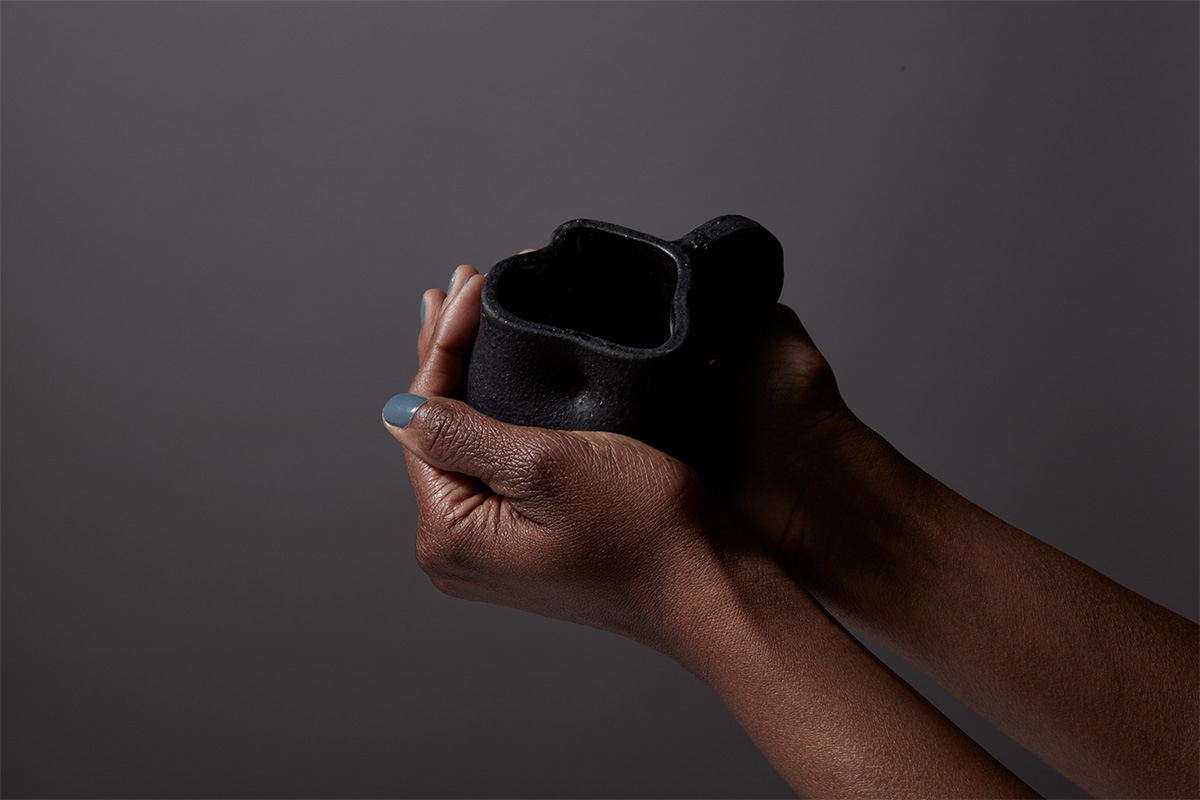 "black tea cup held in two hands in front of dark background"