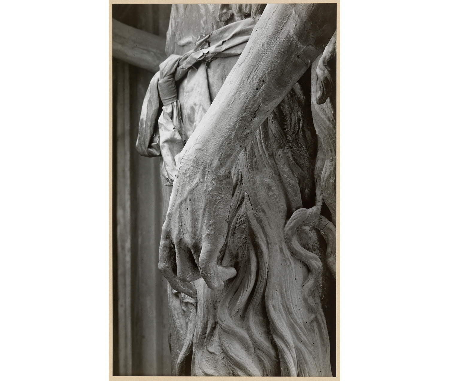 close up of the hand of a sculpture, with the folds of the sculpture's clothing in the background