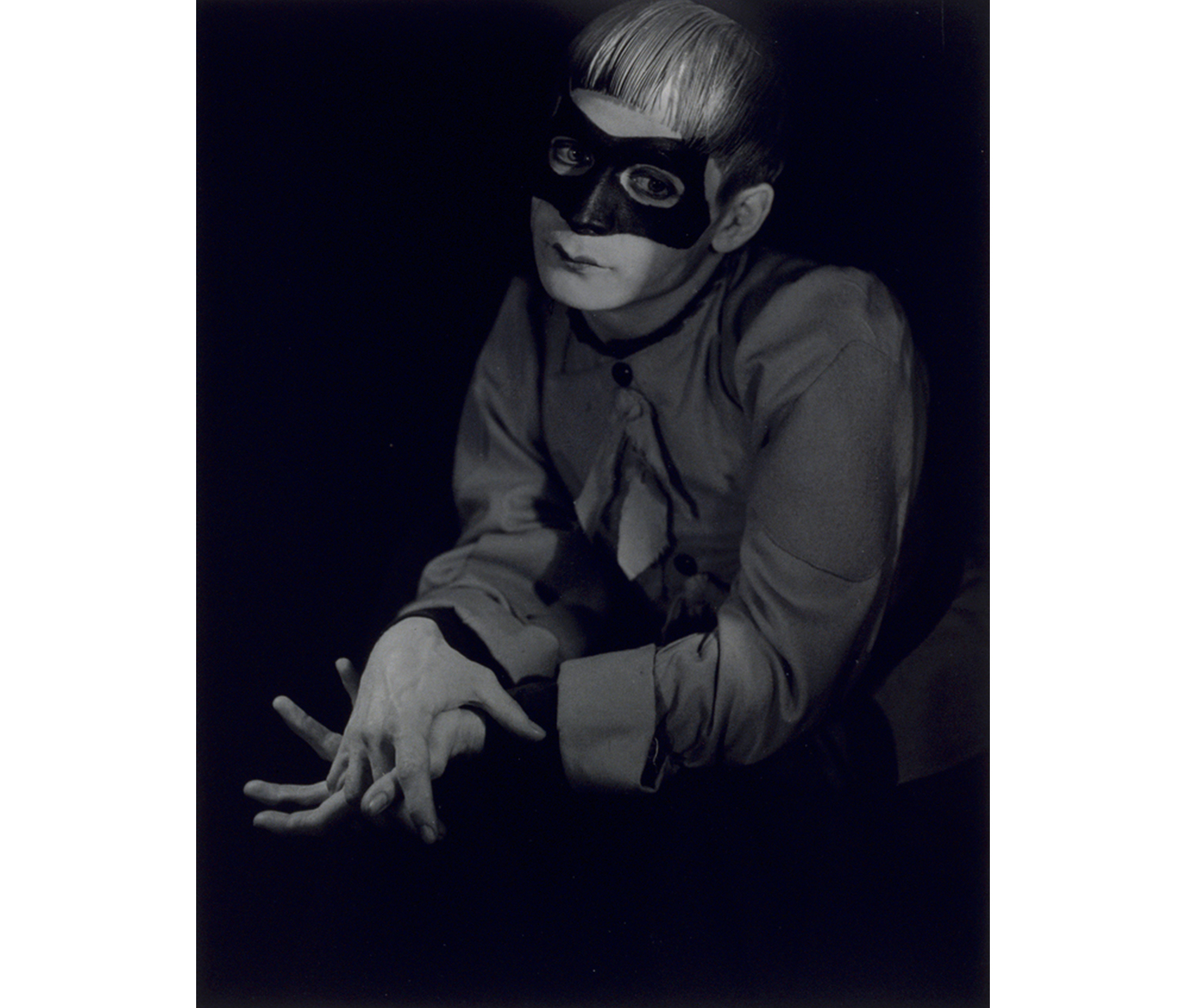 portrait of man wearing mask, with fingers clasped together