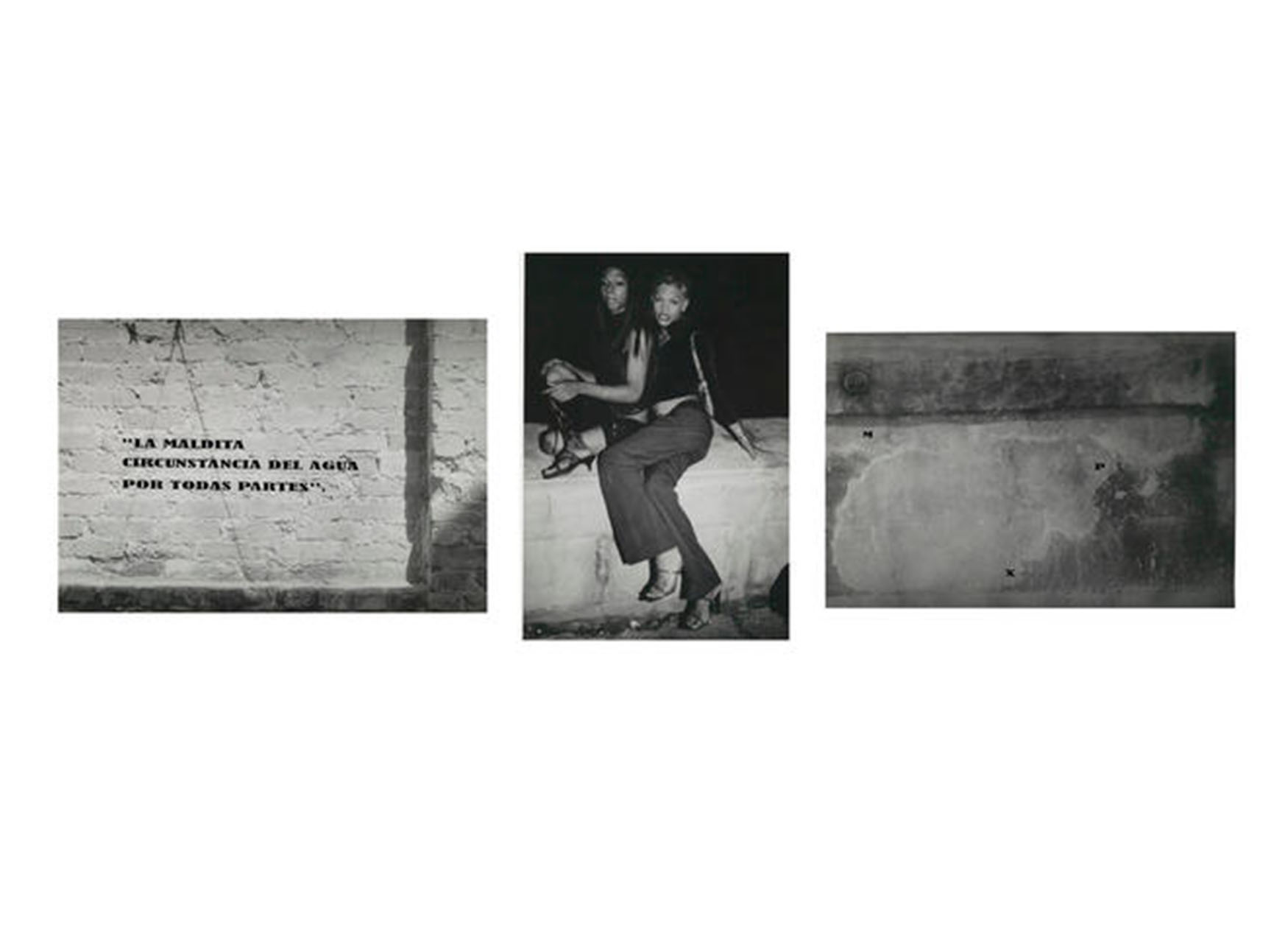 left: brick wall with indentation and applied text: 'LA MALDITA / CIRCUNSTANCIA DEL AGUA / POR TODAS PARTES". middle: night, outdoors, two figures sitting on low concrete wall posing for the camera, one with legs folded, short skirt, top and heeled sandals, other with slacks, short top, purse and heeled sandals. right: concrete wall with applied text M at upper left, P and mid-right, X at lower center