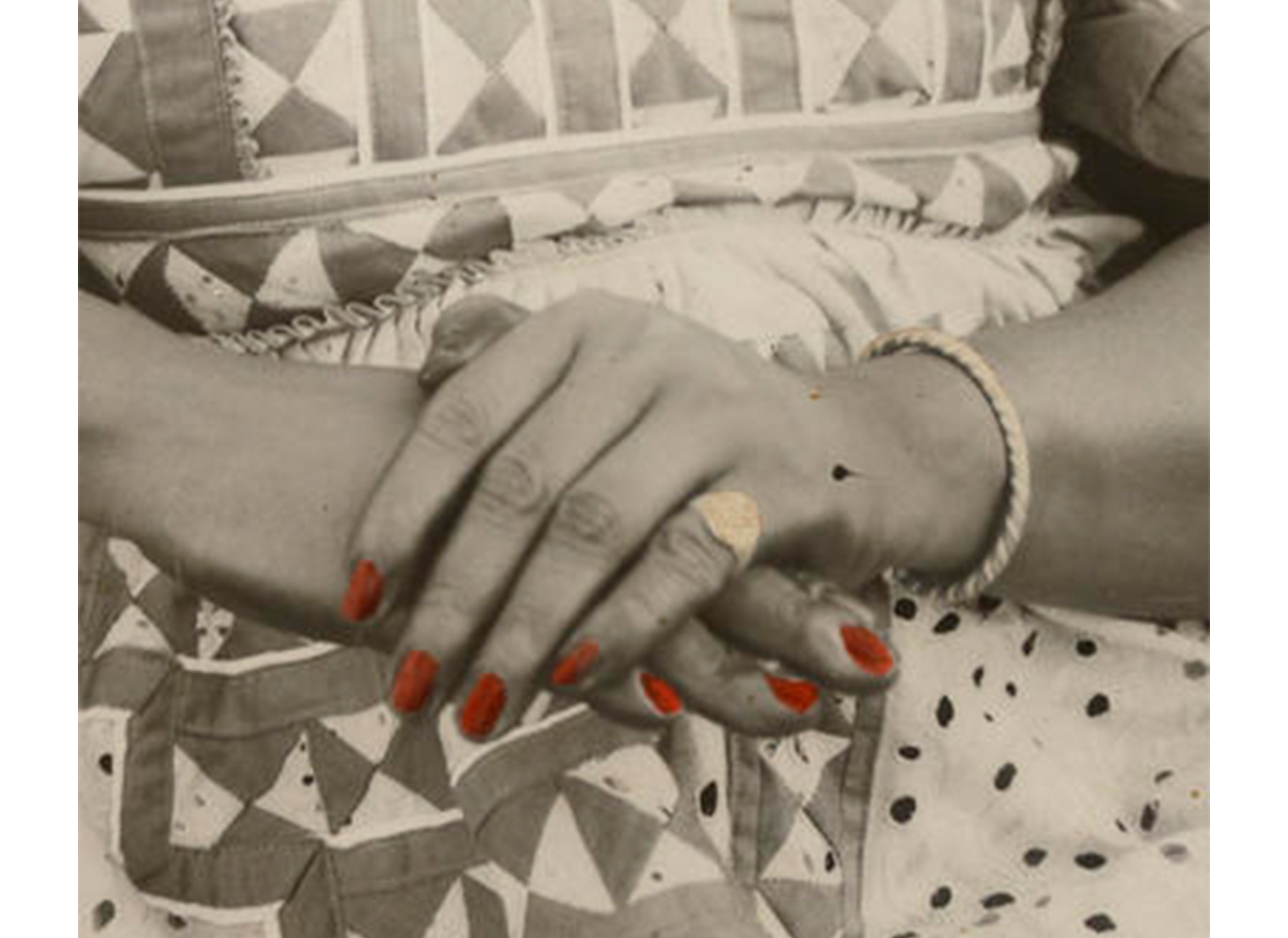 close-up of woman's hands crossed one over the other on her lap; fingernails tinted red