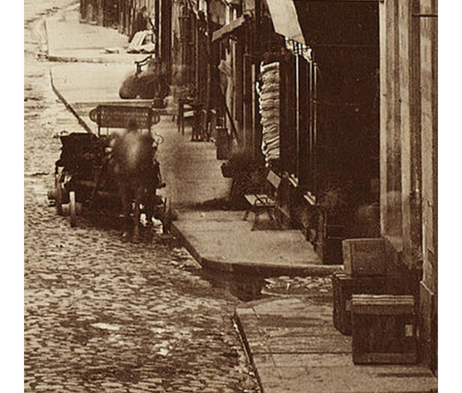 detail of a cart on a cobblestone street, pulled by a blurry horse in motion