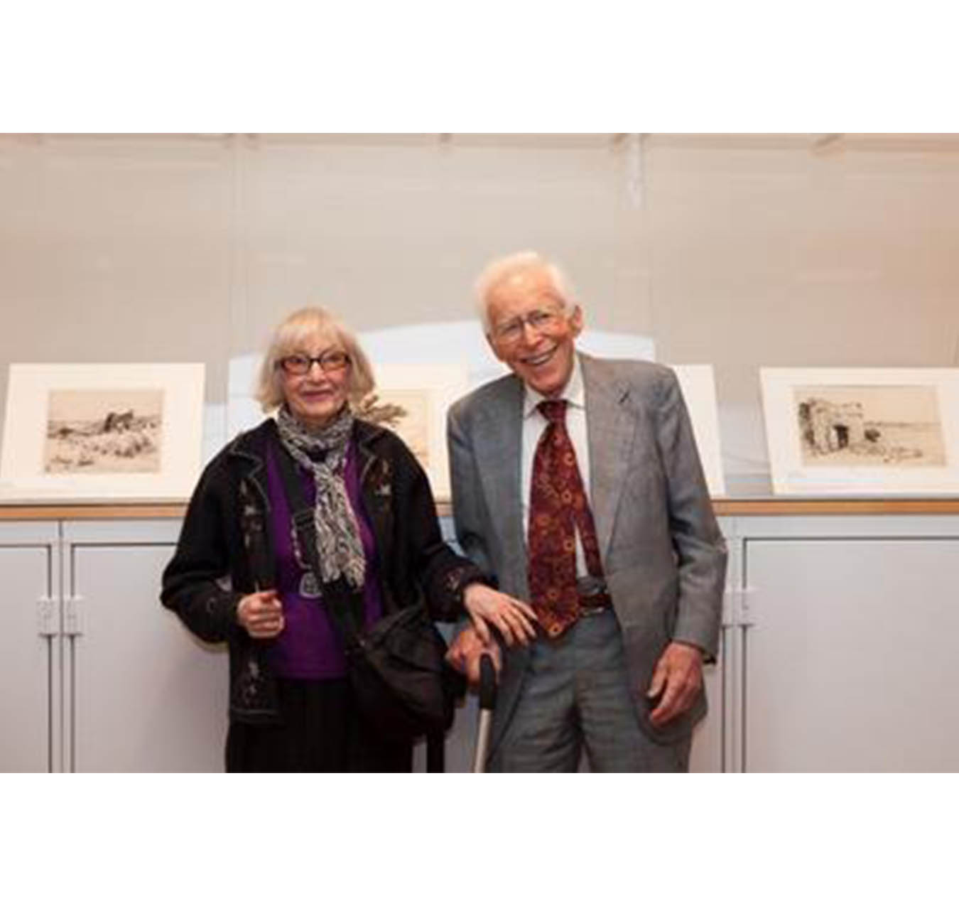 man and woman standing in front of a display of prints on top of a cabinet