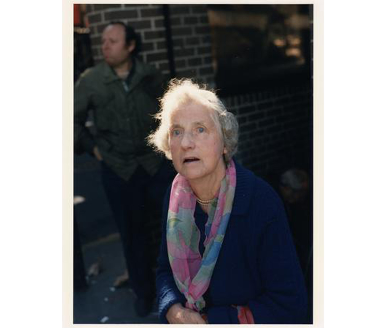 older woman wearing navy top and light pink, green, and blue floral scarf, looking up