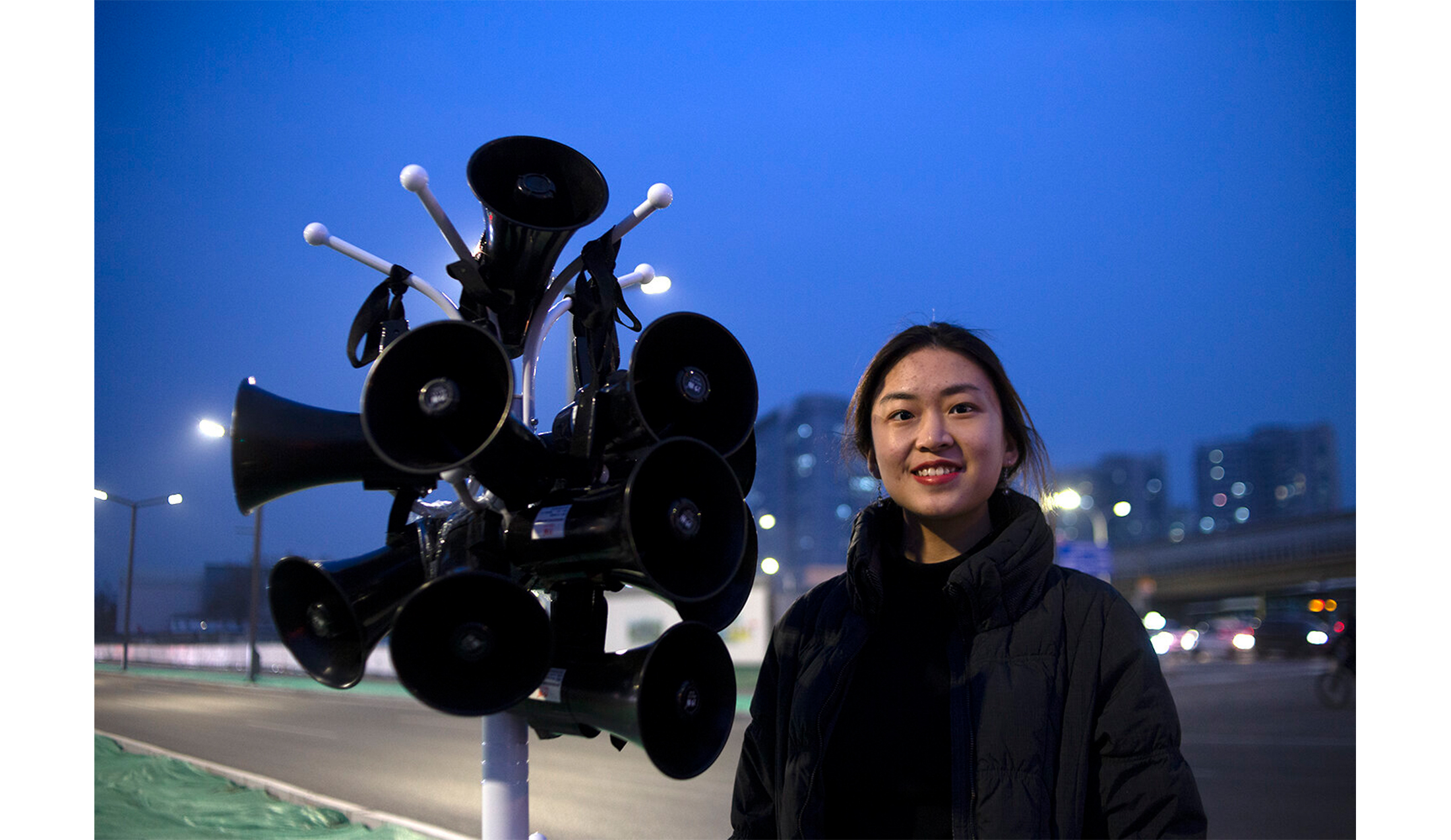 girl standing outside next to a coat-hanger with loudspeakers hanging on it