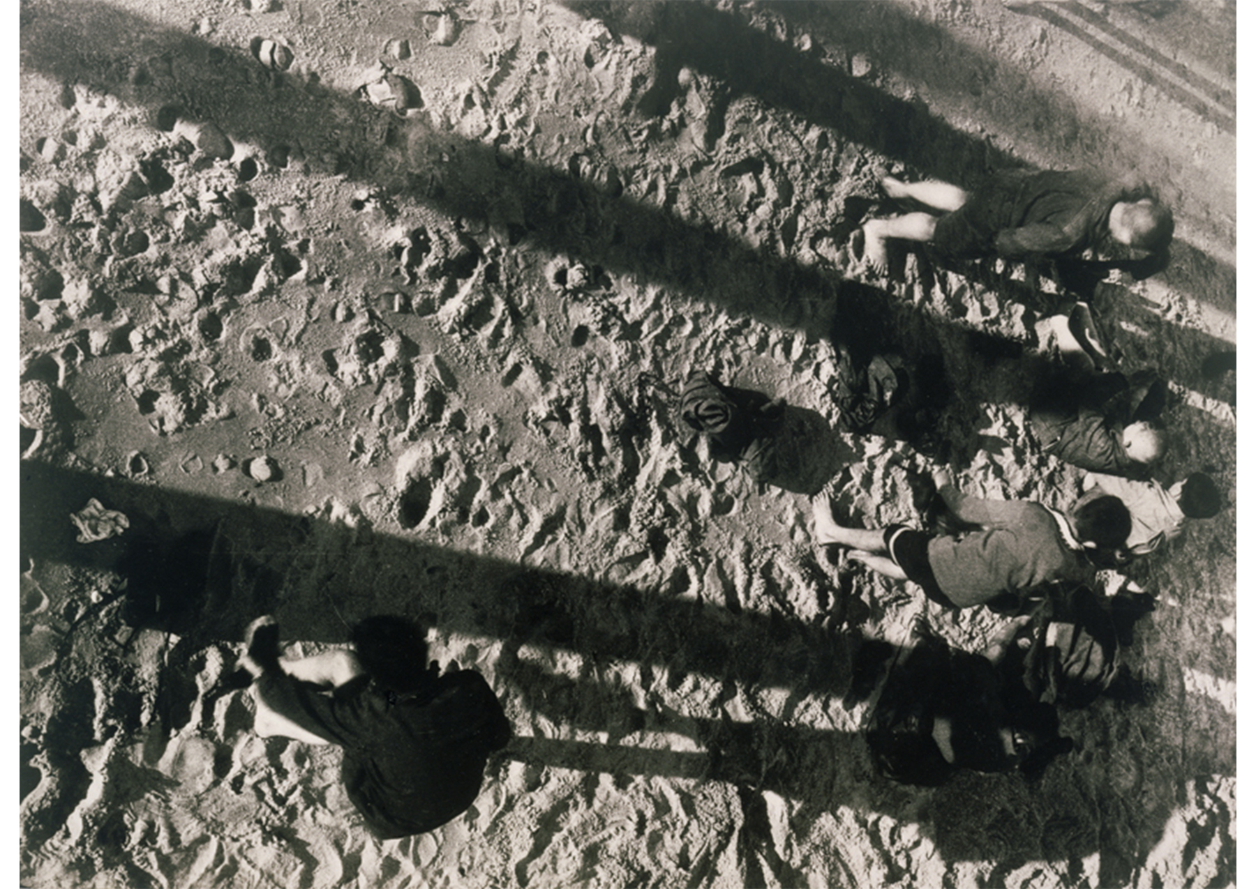 aerial view of children playing in sand, with heavy shadows over the image