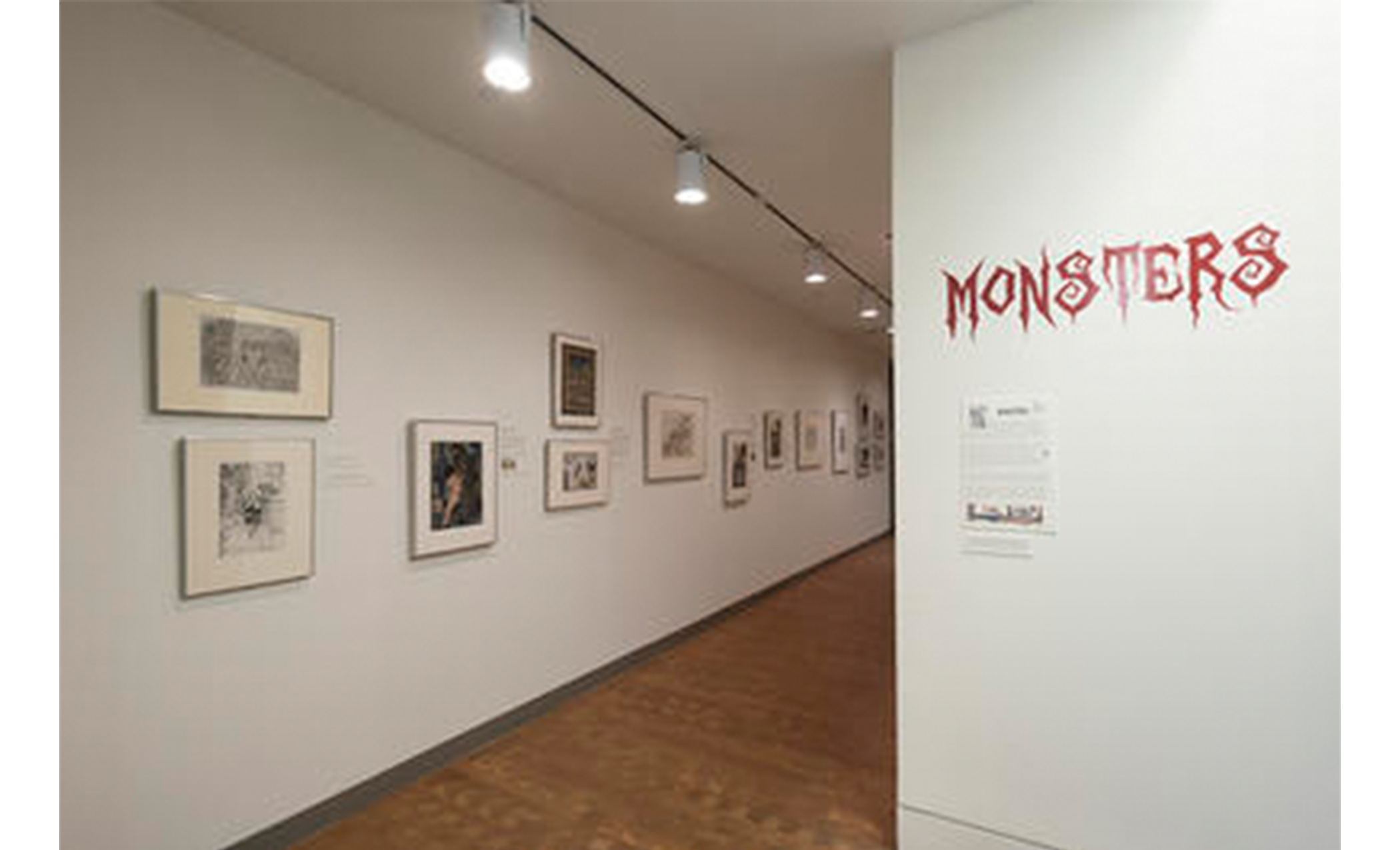 hallway in an art gallery with prints displayed along the walls. red text on the wall at the entrance reads "MONSTERS"