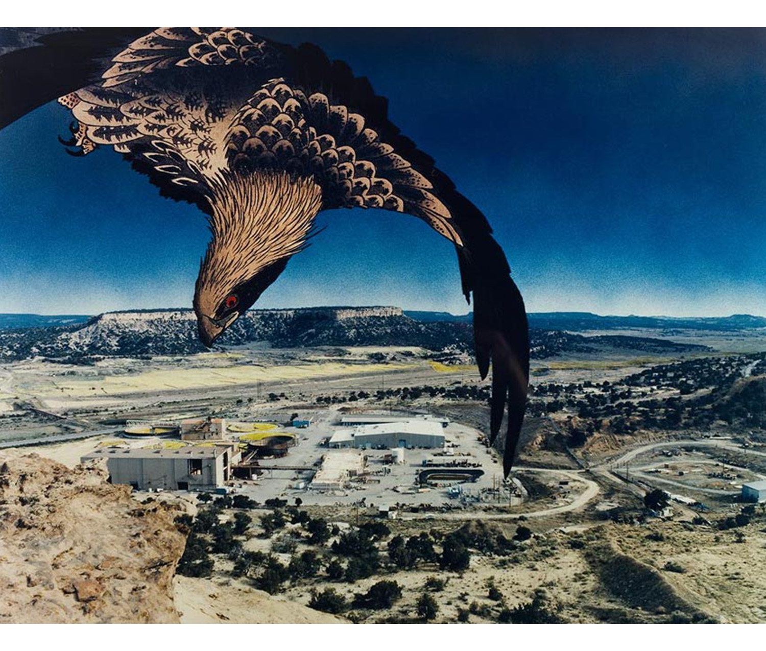 exterior, view from sky of large barren area, low mountains and scrub growth with industrial buildings in center, print image of a flying eagle superimposed on the upper left sky