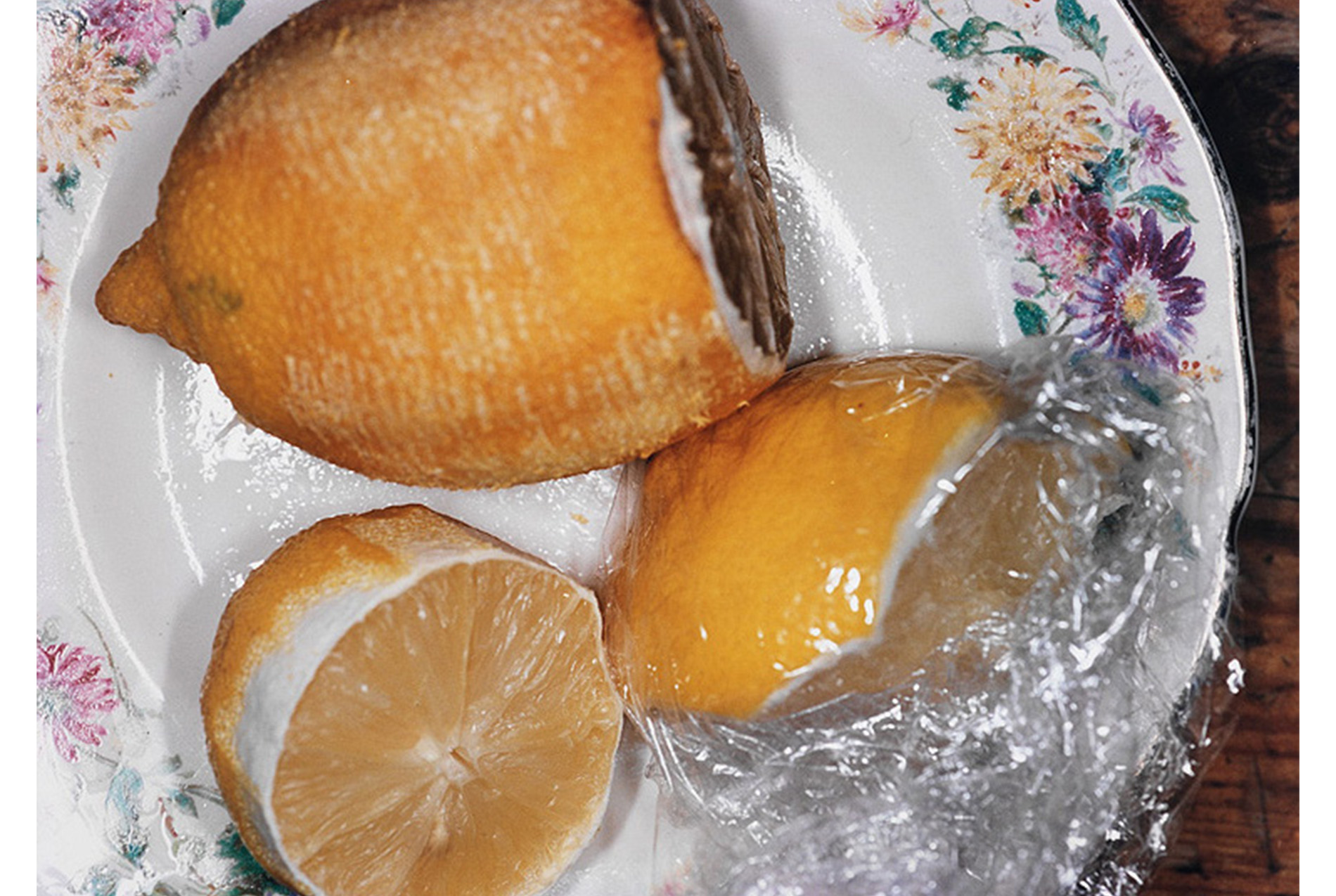 three lemons on a floral plate; plastic wrap
