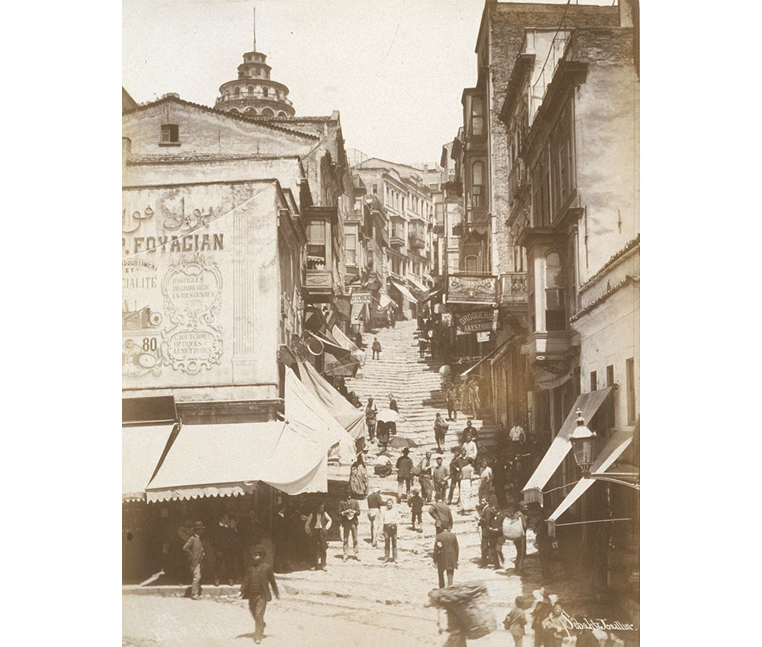 Image of Karaköy region of Istanbul. Galata tower in the background; street scenes with stores and people walking