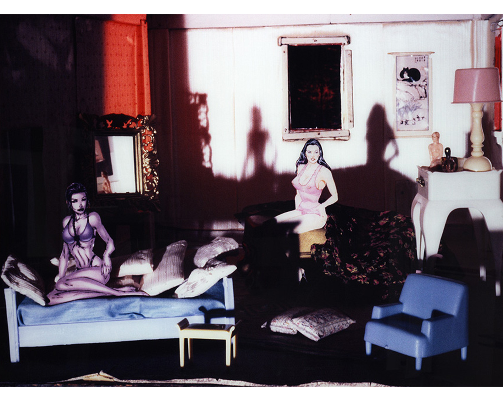 room with gilt mirror on left wall, couch at lower left with woman in underclothes seated on it among many pillows, small table near bed, armchair at lower right, table with lamp and objects at mid-right, scroll on wall, window in back center, unmade bed with floral blanket and woman seated on it wearing bra and underpants