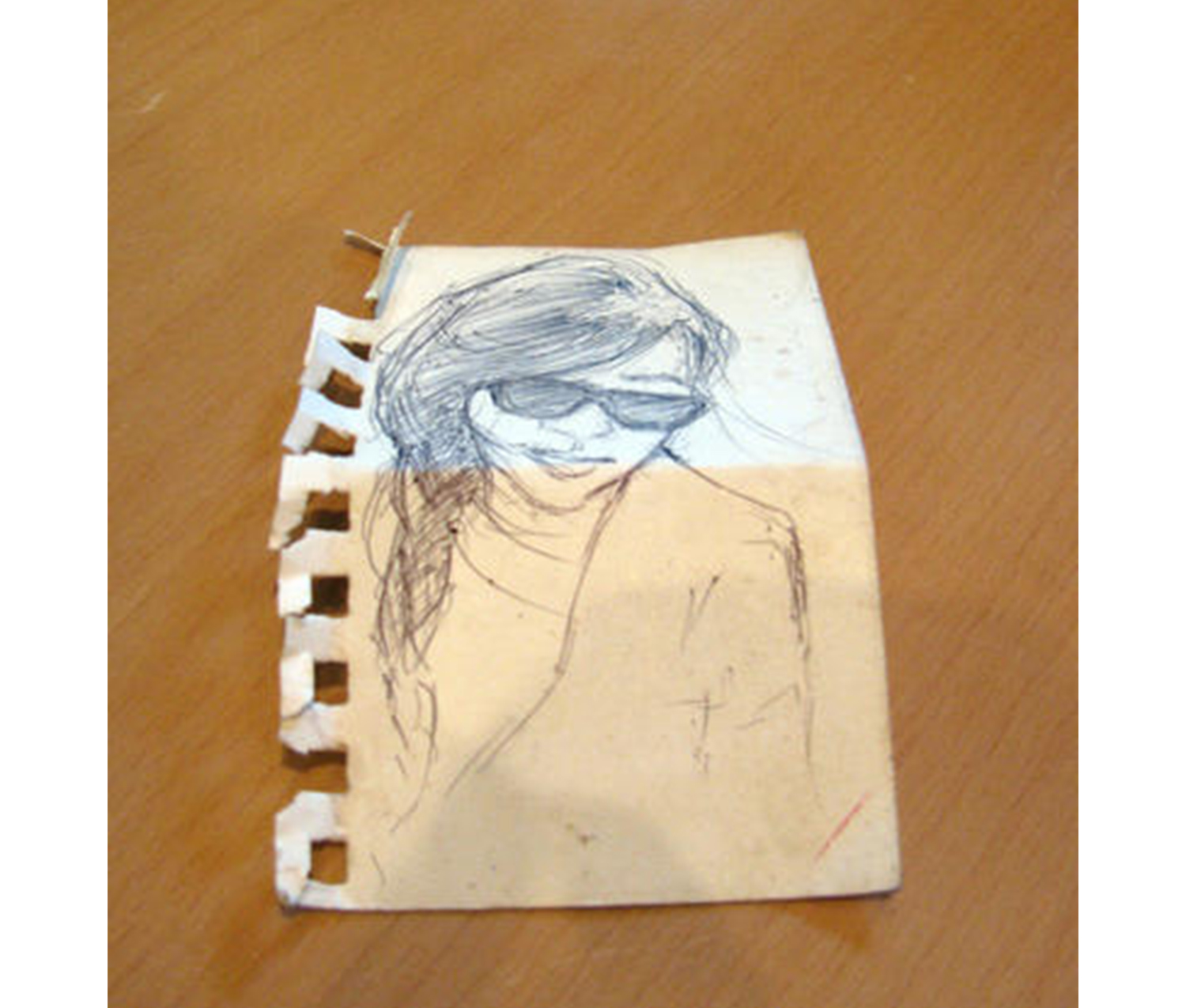 white slip of paper with a sketch of a girl wearing hair in a braid and sunglasses