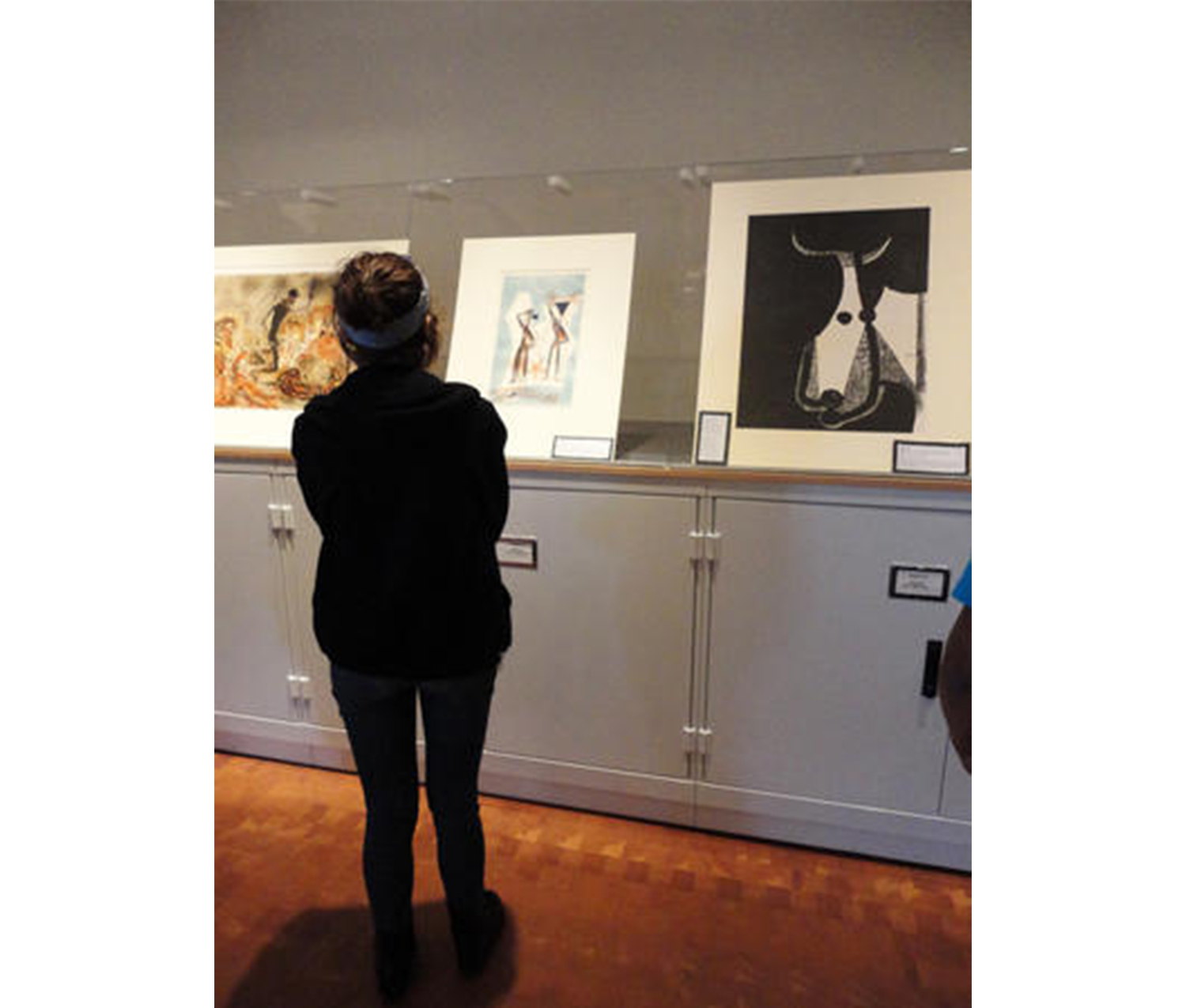 girl stands in front of a gray cabinet with three prints propped up on it