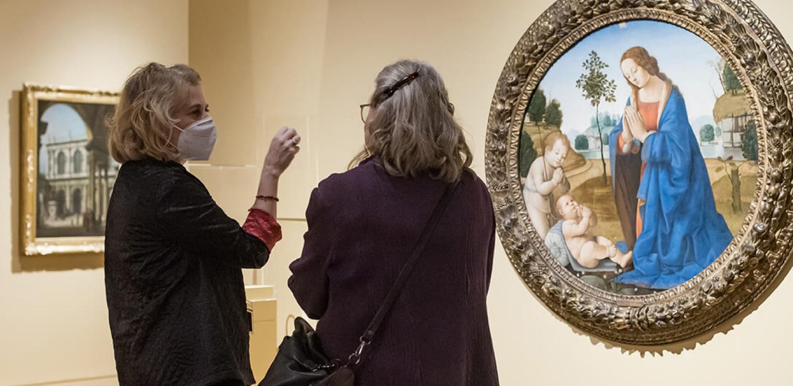 Two women talking in front of a piece of art in the gallery