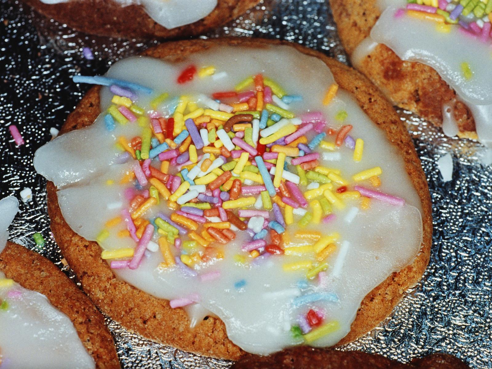 Close up of cookie with frosting and rainbow sprinkles by Martin Parr.