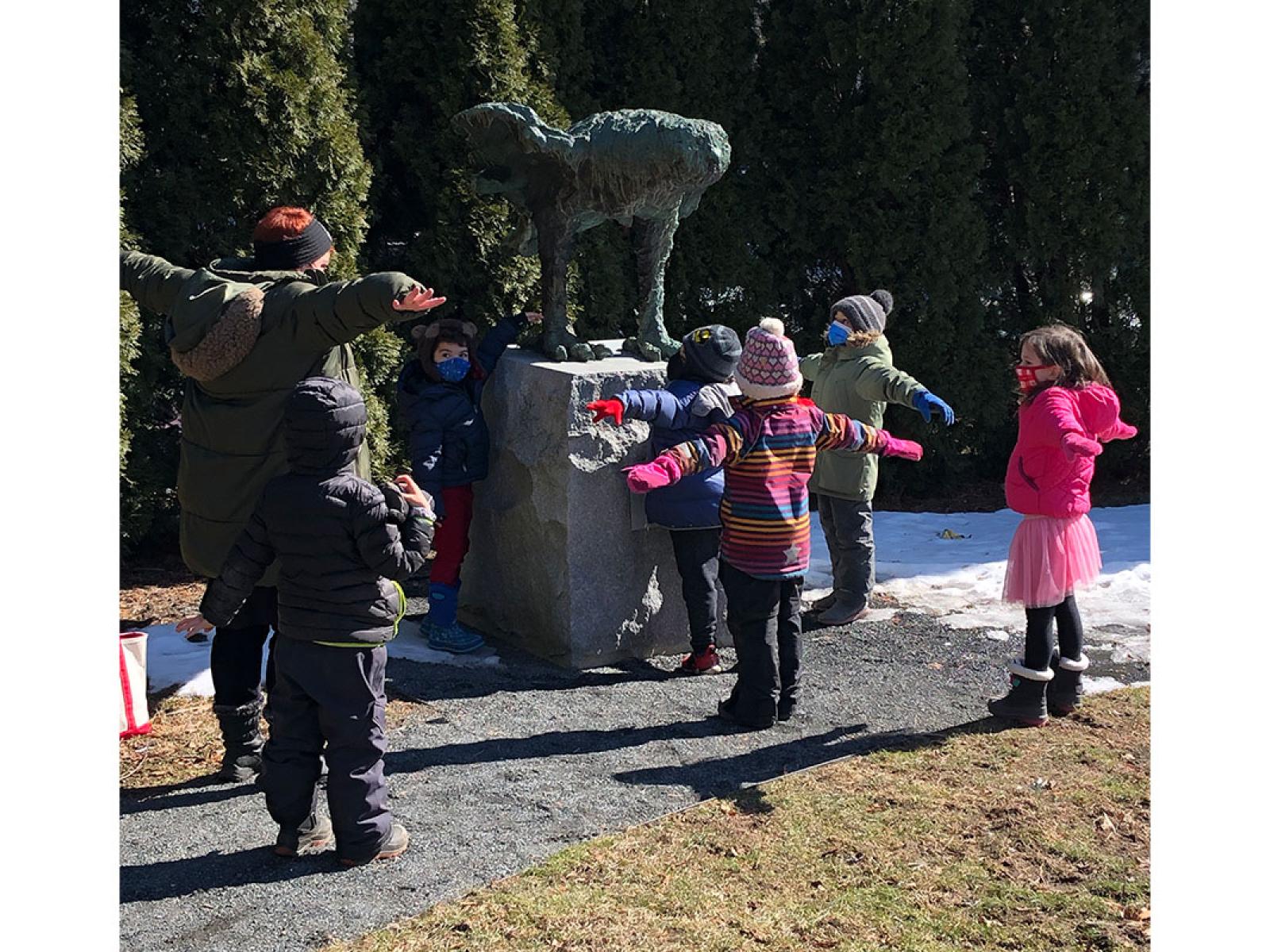 Children on outdoor tour looking at an Owl sculpture and mimicking its gesture