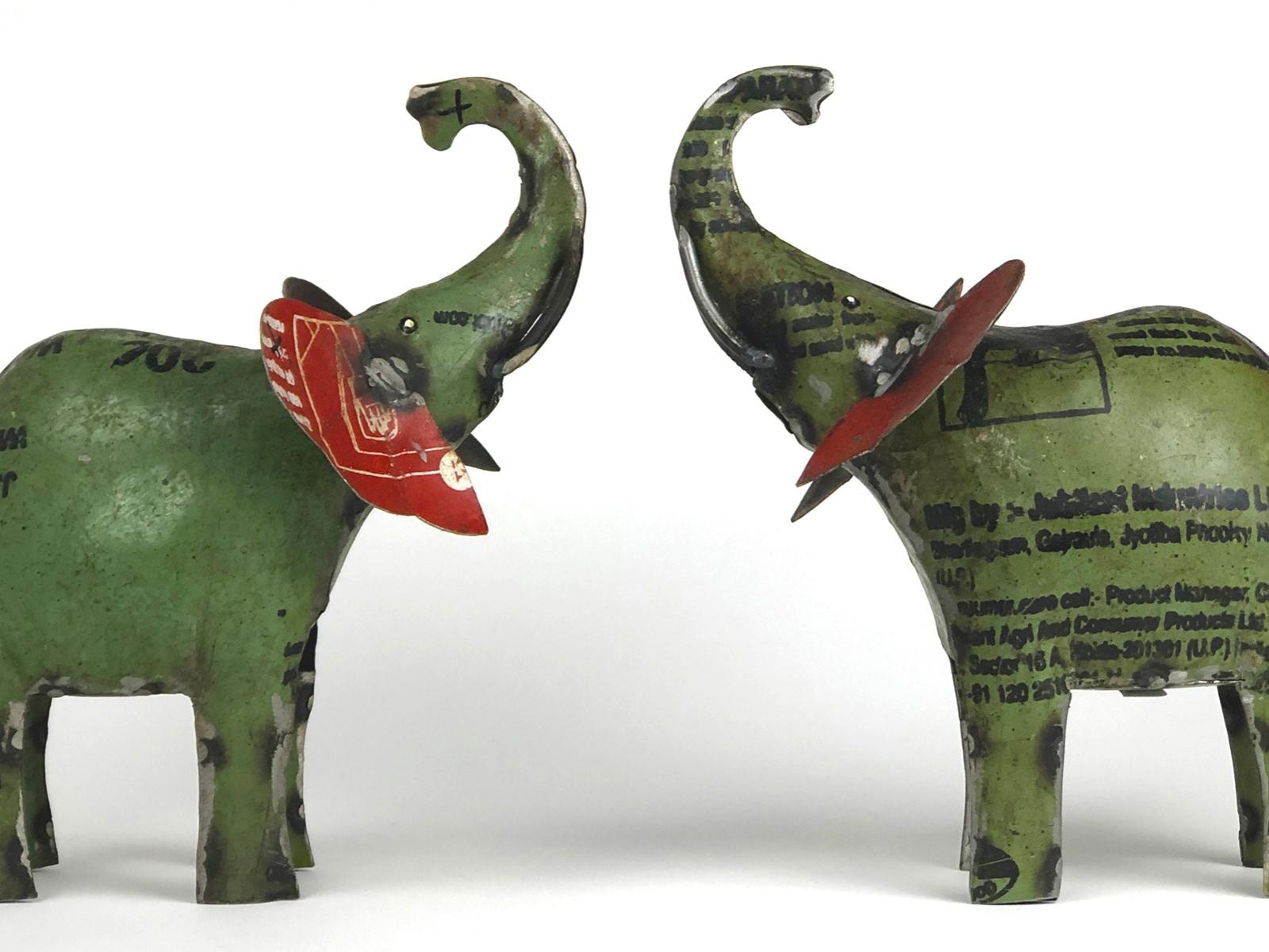 Two metal green elephant toys facing each other on a white background