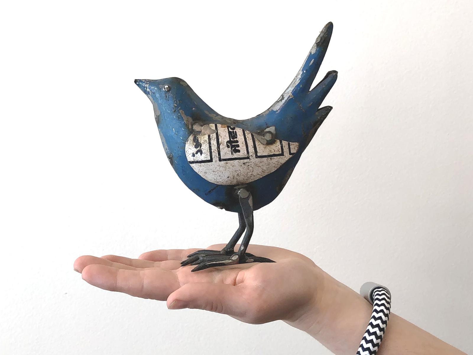 hand holding a blue metal bird