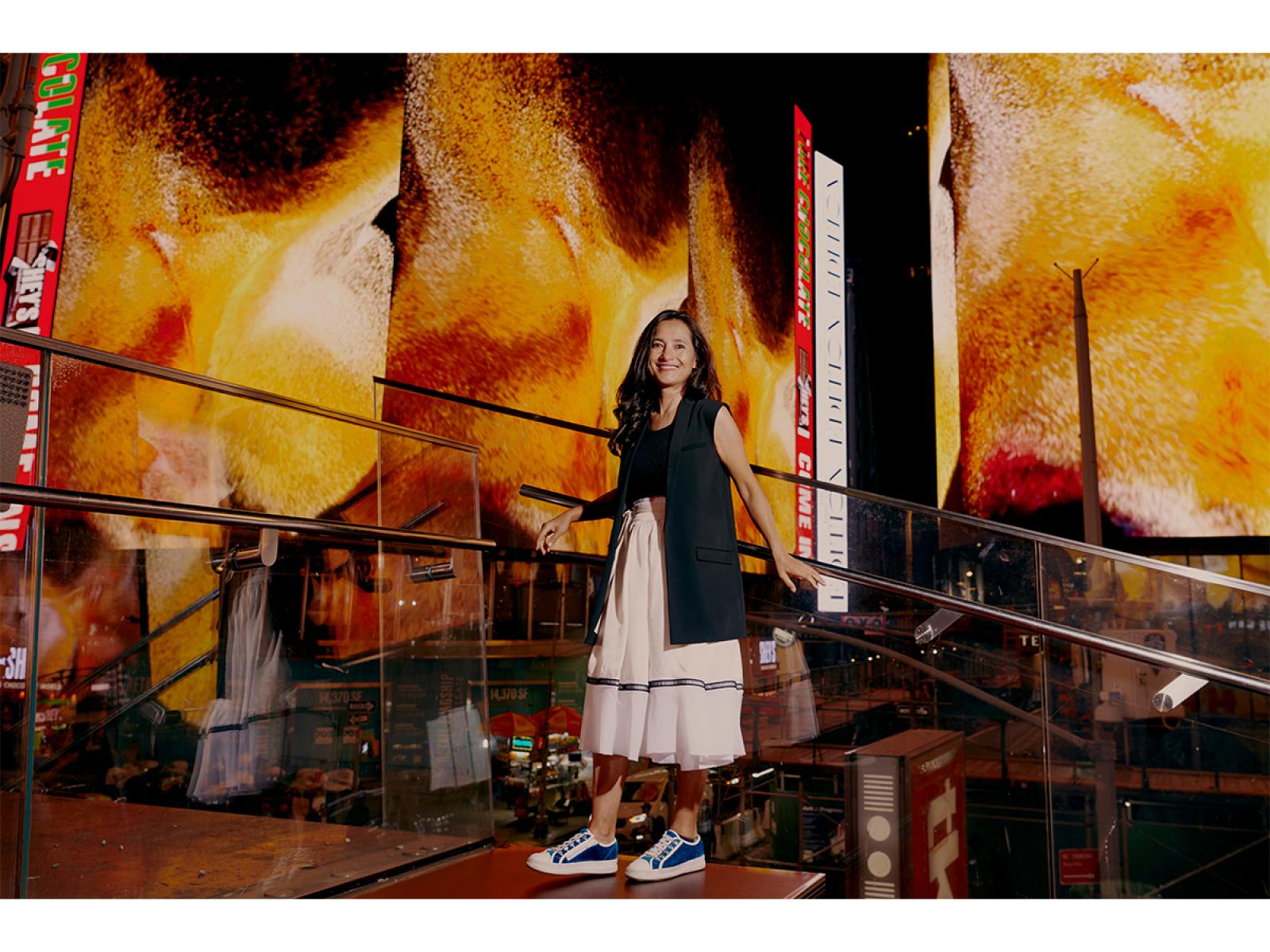 Photo of a woman standing in front of large virtual billboards in Times Square