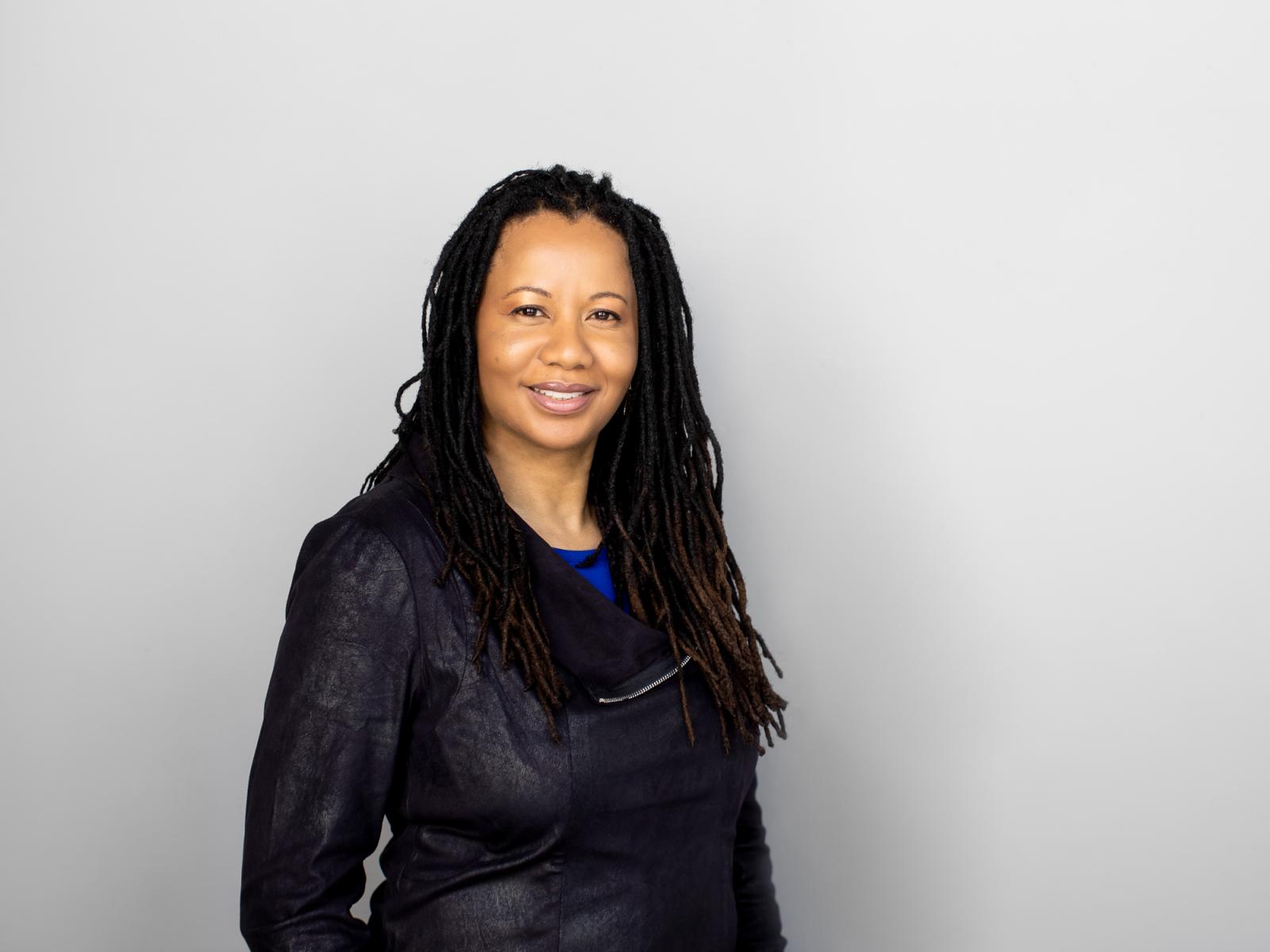 A woman standing with long braids and a black outfit