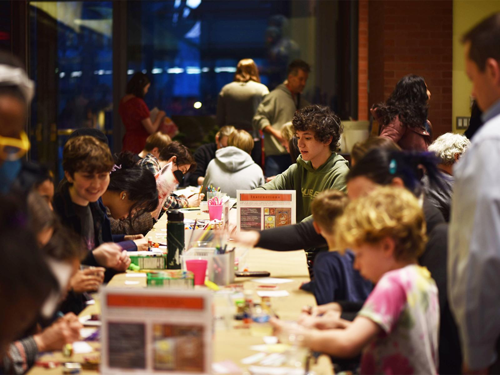 People of all ages sitting at tables and making art