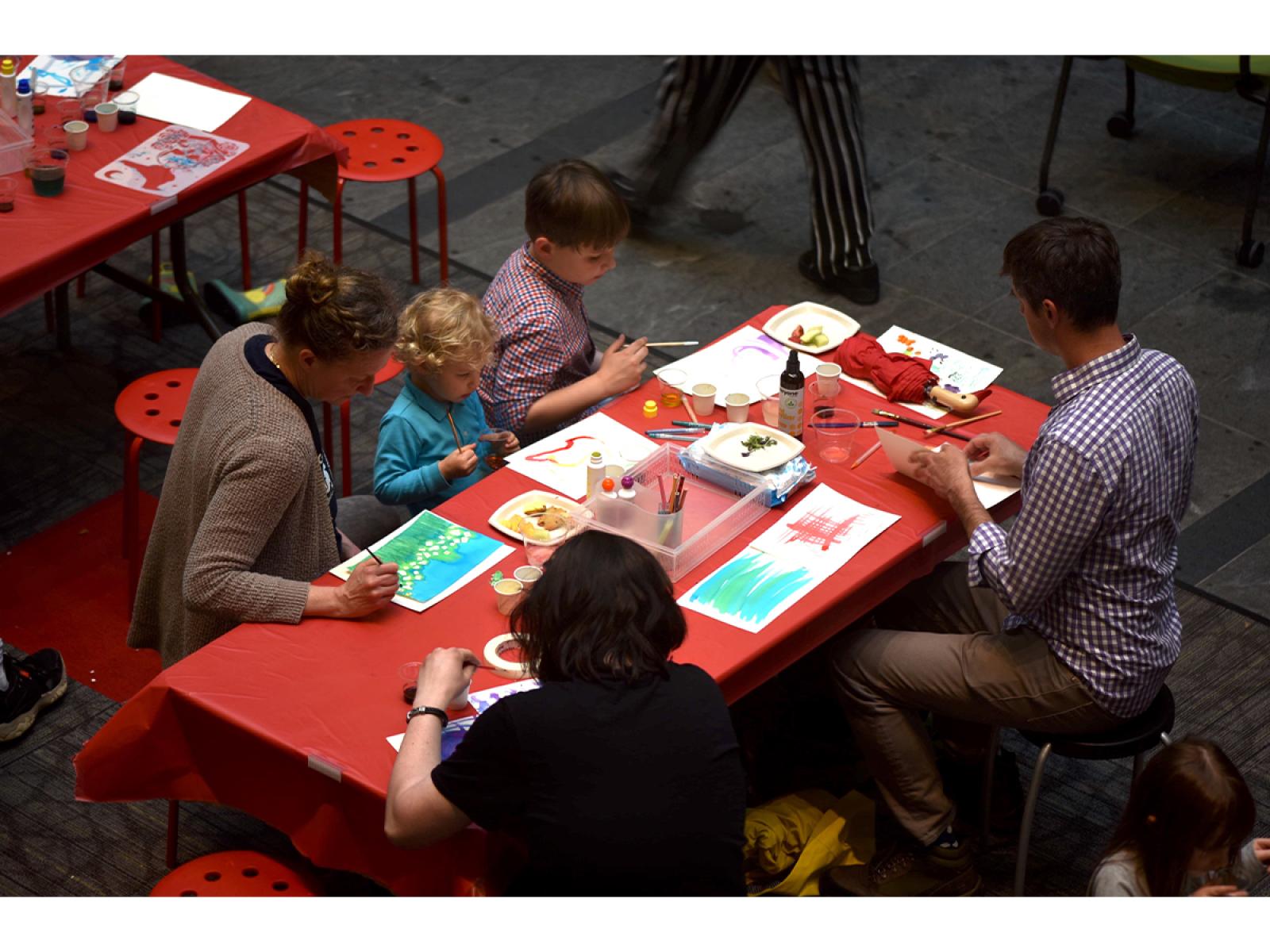 Bird eye view of people of varying ages sitting at tables making art