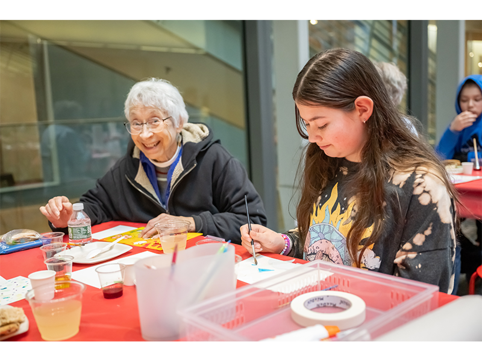 Two people sitting at a tablemaking art, both are smiling
