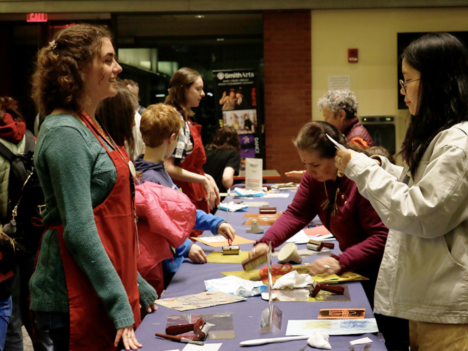 Six people of varying ages standing around a table with art making materials