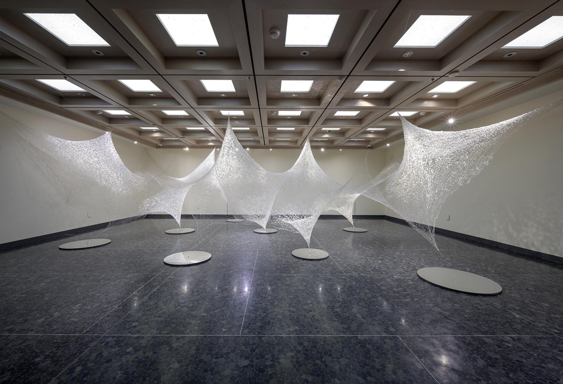 Webbed material hanging in a gallery in several places from ceiling to the floor