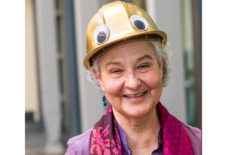 Person with gold hard hat on with googly eyes on it