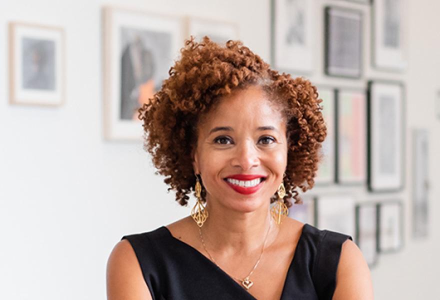 Portrait of a person with curly short auburn hair with black dress on and