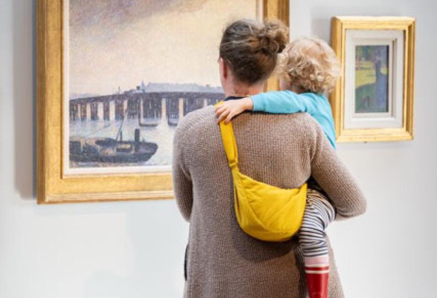 An adult and child in front a a painting on a gallery wall