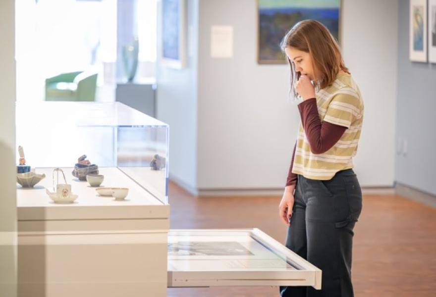 Person looking at a drawer of art artwork in a gallery