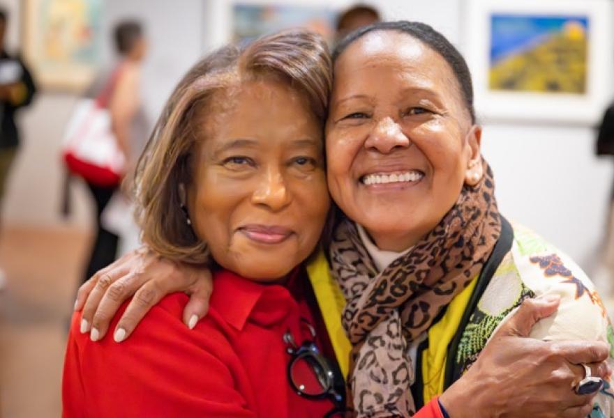 Two people hugging and looking at the viewer