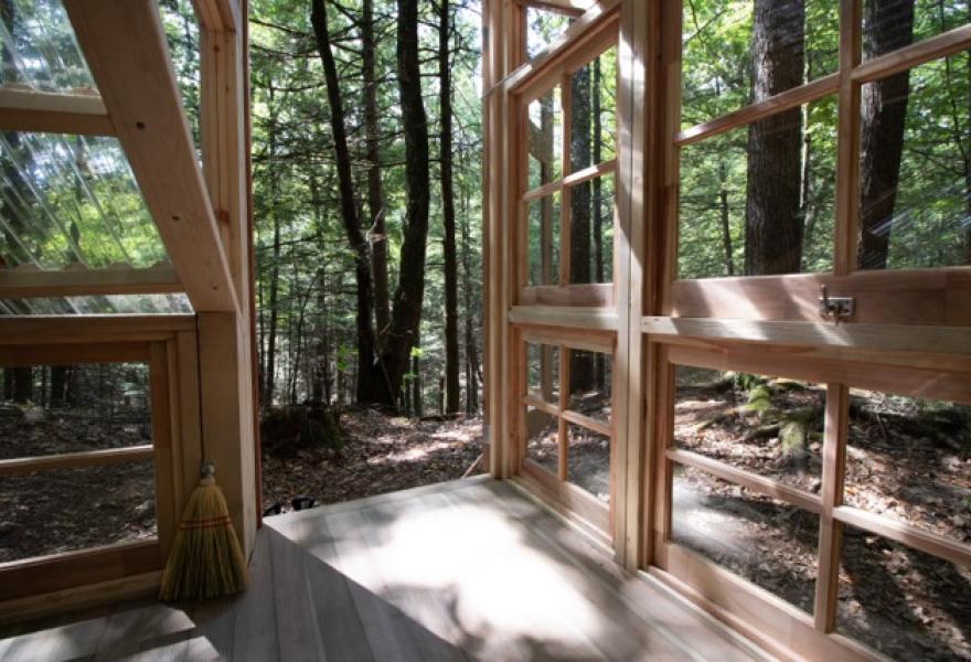 View from inside a wooden structure with windows in the woods