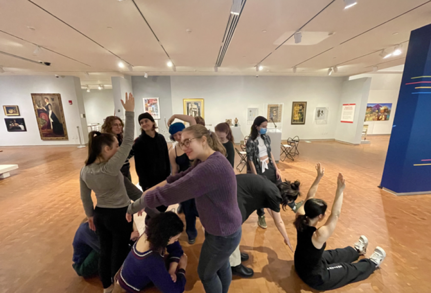 Group of students in a gallery posing in postures on the floor, standing, bending and standing