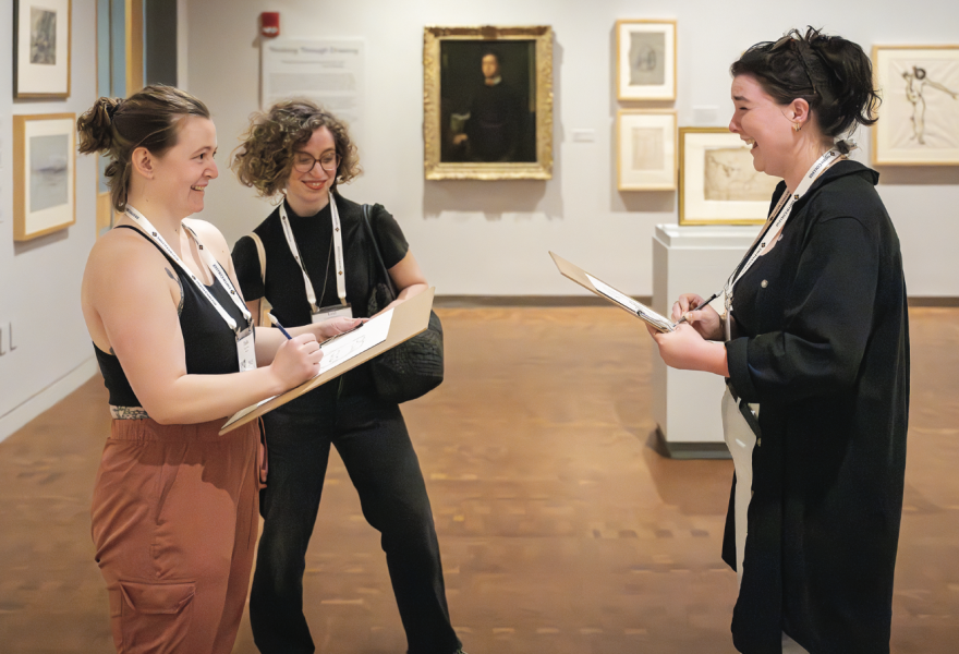 Three people in gallery, two of them drawing the other
