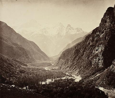 black and white image of three large mountains, with a body of water in the center