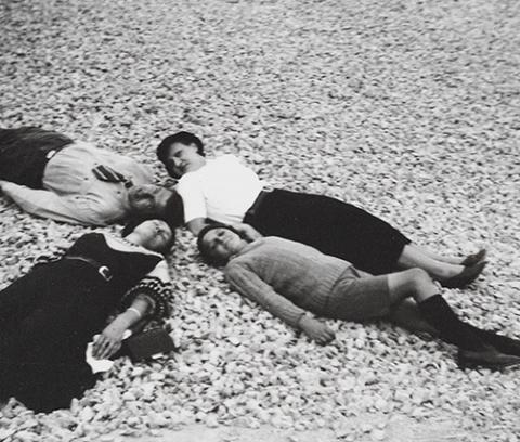 four people, three women and one man, lying on the ground with heads together