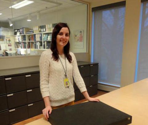 girl standing behind a wooden table with a black box on it