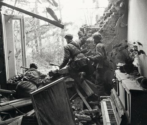 soldiers stand with rifles, gathering at the opening of a building. piano sitting behind them