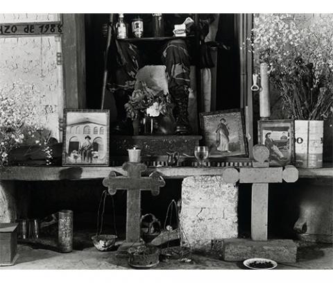 interior, home-made altar with candles, crosses, pictures of saints, older men, flowers, cigarettes, alcohol, Crush soda, cooking pots and a plate of coffee beans