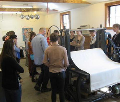 art studio, group of people standing around a printing press