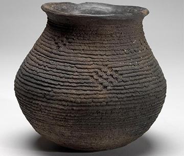 large vessel made from dark clay with imprinted woven design on surface